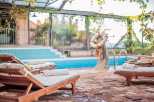Hotel Monte Turri - Adults Only في ارباتاكس: امرأة تقف بجوار حمام السباحة