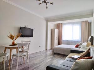 une chambre avec un lit, une table et un canapé dans l'établissement Студия КОЛОС в центре с шикарным видом из окна, à Almaty