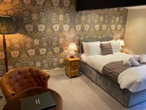 ein Schlafzimmer mit einem Bett, einem Stuhl und einem Tisch in der Unterkunft Black Lion Hotel Richmond North Yorkshire in Richmond