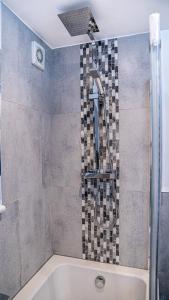 uma casa de banho com um chuveiro e uma banheira em The Duplex Margate with Deck, Mini Bar & Air Conditioning em Margate