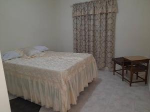 a bedroom with a bed and a table and a window at casa equipada estadia placentera in Hainamosa
