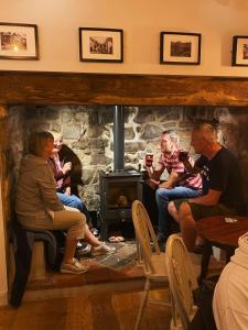 a group of people sitting in front of a fireplace at Tafarn Yr Heliwr in Nefyn