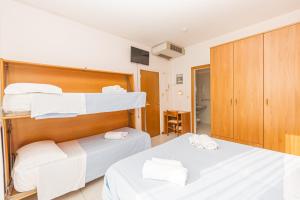 um quarto com 2 camas e toalhas brancas em Hotel Arlino em Rimini