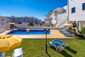 a pool with chairs and umbrellas on a building at Apartamentos Carruna in Albufeira