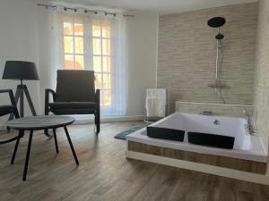 - un salon avec une baignoire et une chaise dans l'établissement Magnifique Loft 35m2 Jacuzzi RVB NIGHT 1, à Amiens