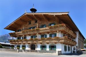 un edificio con techo de madera con flores. en Kaiserpension Müllnerhof en Oberndorf in Tirol