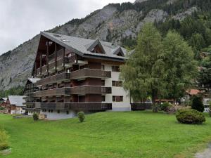 a large building with a grassy field in front of a mountain at Studio spacieux au pied des pistes avec casier à skis - FR-1-692-31 in La Chapelle-dʼAbondance