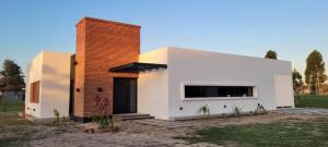 a white house with a brick chimney at Guyra, Casas Boutique in Corrientes