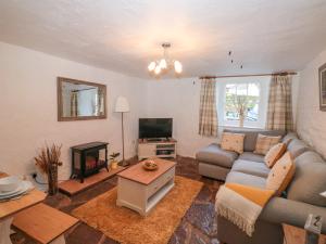 a living room with a couch and a tv at Honeysuckle Cottage in Paignton