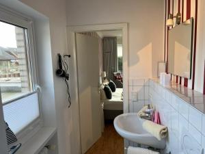 a white bathroom with a sink and a mirror at Sonnenaufgang in Westerland