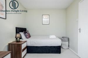 Habitación blanca con cama y mesita de noche en Dwellers Delight Living Ltd Serviced accommodation 2 Bed House, free Wifi & Parking, Prime Location London, Woodford, en Woodford Green