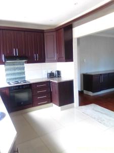 a kitchen with wooden cabinets and a stove top oven at Mkhandi Self Catering in Durban