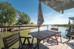 a wooden table and chairs on a deck next to the water at Hafenresort Karnin Hausboot Glaukos in Karnin