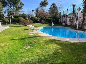 a swimming pool in a yard with a grass field at Luxurious 5 Bedroom Apartment in Moncloa-Aravaca in Madrid