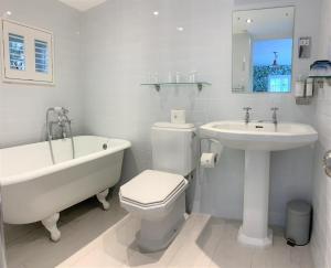 a bathroom with a tub and a toilet and a sink at Ferryman`s Cottage at The Beetle & Wedge in Moulsford
