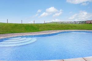 a large swimming pool with a grassy hill in the background at 10 Oceans Edge in Kingsbridge