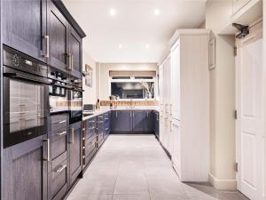 a large kitchen with black cabinets and a tile floor at Hillcrest House in Ashbourne