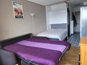 um quarto com 2 camas e um cobertor roxo em STUDIO plein sud "Les Arolles" Balcon de VILLARD DE LANS em Villard-de-Lans