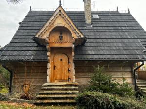 een klein huis met een houten deur en trap bij Chata w chmurach in Gliczarów