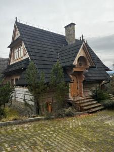 a large wooden house with a black roof at Chata w chmurach in Gliczarów