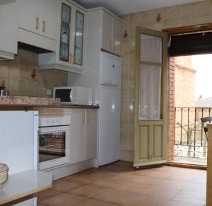 cocina con armarios blancos y puerta abierta en Casa Rural La Callejuela en Ayllón