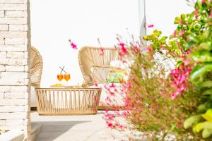 un patio con 2 sillas de mimbre y flores en Il Moro Camere&Relax, en San Vito lo Capo