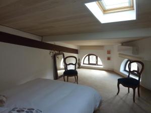 ein Schlafzimmer mit 2 Stühlen und einem Bett und einem Dachfenster in der Unterkunft Beaux Chênes in Nérac