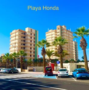 un aparcamiento con palmeras frente a un edificio en Miss Flora playa honda, en Playa de las Américas