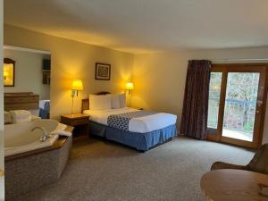Four Seasons Inn في ماجي فالي: غرفة في الفندق مع سرير وحوض استحمام
