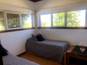 1 dormitorio con 2 camas y 2 ventanas en Casaquinta La Morena en Azul