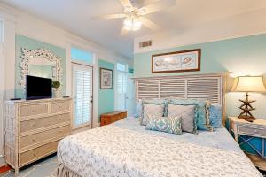a bedroom with a bed with a ceiling fan and a television at True Knot Cottage in Saint Simons Island
