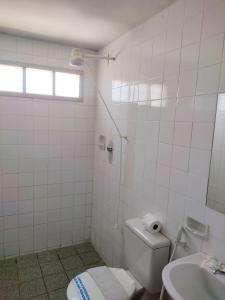 a white bathroom with a toilet and a sink at Santorini Praia Hotel in Natal