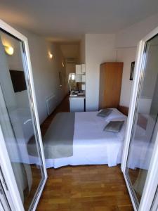 1 Schlafzimmer mit einem großen weißen Bett und einer Küche in der Unterkunft Pluton in Primošten