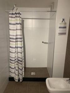 y baño con cortina de ducha y lavamanos. en Puerto Aventura, en Montevideo
