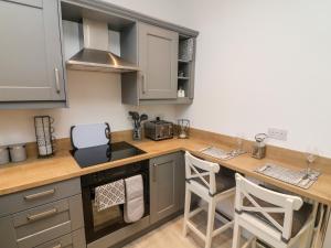 a kitchen with a counter and some stools in it at Myrtle Cottage in Preston