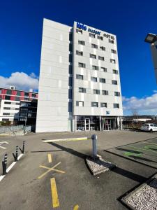 a large building with a parking lot in front of it at Ibis budget Lausanne-Bussigny in Lausanne
