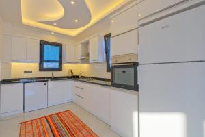 una cocina con armarios blancos y alfombra naranja en Alternatif Villaları, en Fethiye