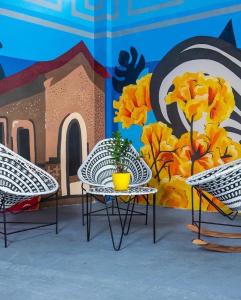 2 sillas y una mesa frente a un mural en hotel nativo, en Valledupar