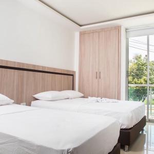 2 camas blancas en un dormitorio con ventana en hotel nativo en Valledupar