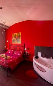 Dormitorio rojo con cama y bañera en Villa Gaia - Luxury Villa, pool & wellness rooms, en Bordighera