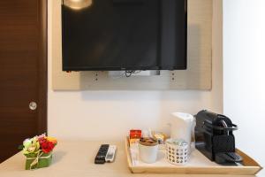 - une table avec une télévision, une cafetière et des fleurs dans l'établissement Cola Di Rienzo Suite Guest House, à Rome