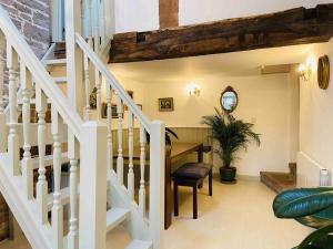 a living room with a staircase and a table and a stair case at The Owl House Cottage in Welsh Newton Common