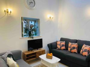 sala de estar con sofá negro y TV en The Owl House Cottage, en Welsh Newton Common