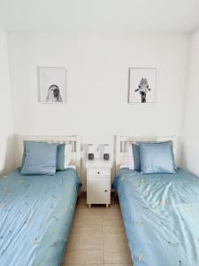 2 camas en un dormitorio con sábanas azules y escritorio en Newly Refurbished Apartment, en Cuevas del Almanzora