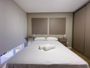 1 dormitorio con 1 cama blanca grande y 2 toallas en LOCAR-IN GRAMADO - Apto Residencial Borges 4901, en Gramado