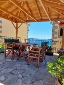una mesa de madera y sillas en un patio con vistas al océano en Studios Edem, en Agios Ioannis Kaspaka