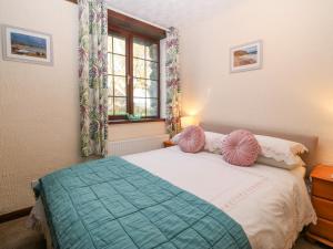 a bedroom with a bed with pink pillows and a window at Trem Y Wyddfa in Gaerwen