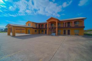 a large yellow building with a large parking lot at Texas Inn San Benito near Harlingen in San Benito