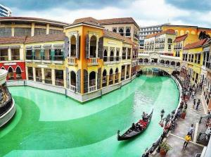 a green water canal with gondolas in a city at Morgan Suite BGC Shortwalk2 Venice Mall free pool gym in Manila