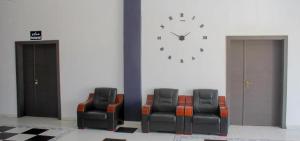 three chairs in a waiting room with a clock on a wall at Andalusia Hotel in Nouakchott